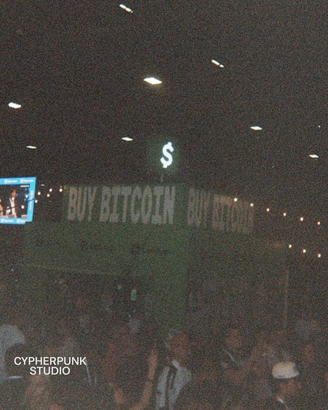 BUY BITCOIN, twice over, in lights above the crowd at night